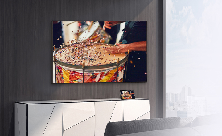 In the room, a wall-mounted TV is set up, with a tablet placed on the shelf. The tablet’s content is mirrored and displayed on the TV.