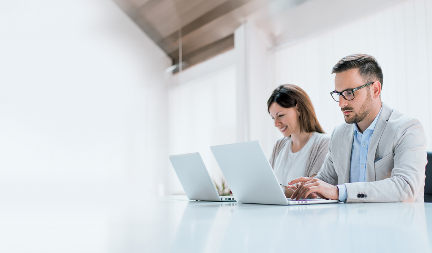Two administrators are managing devices using LG SuperSign Control+ on personal PCs.