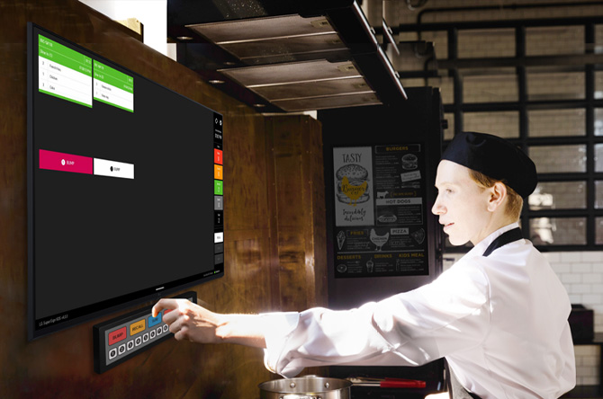 A kitchen staff member is checking order details on the kitchen display.