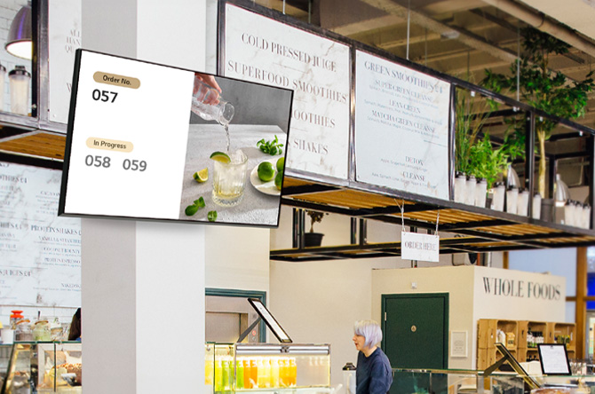 A signage screen mounted on a store wall displays menu images and related information.